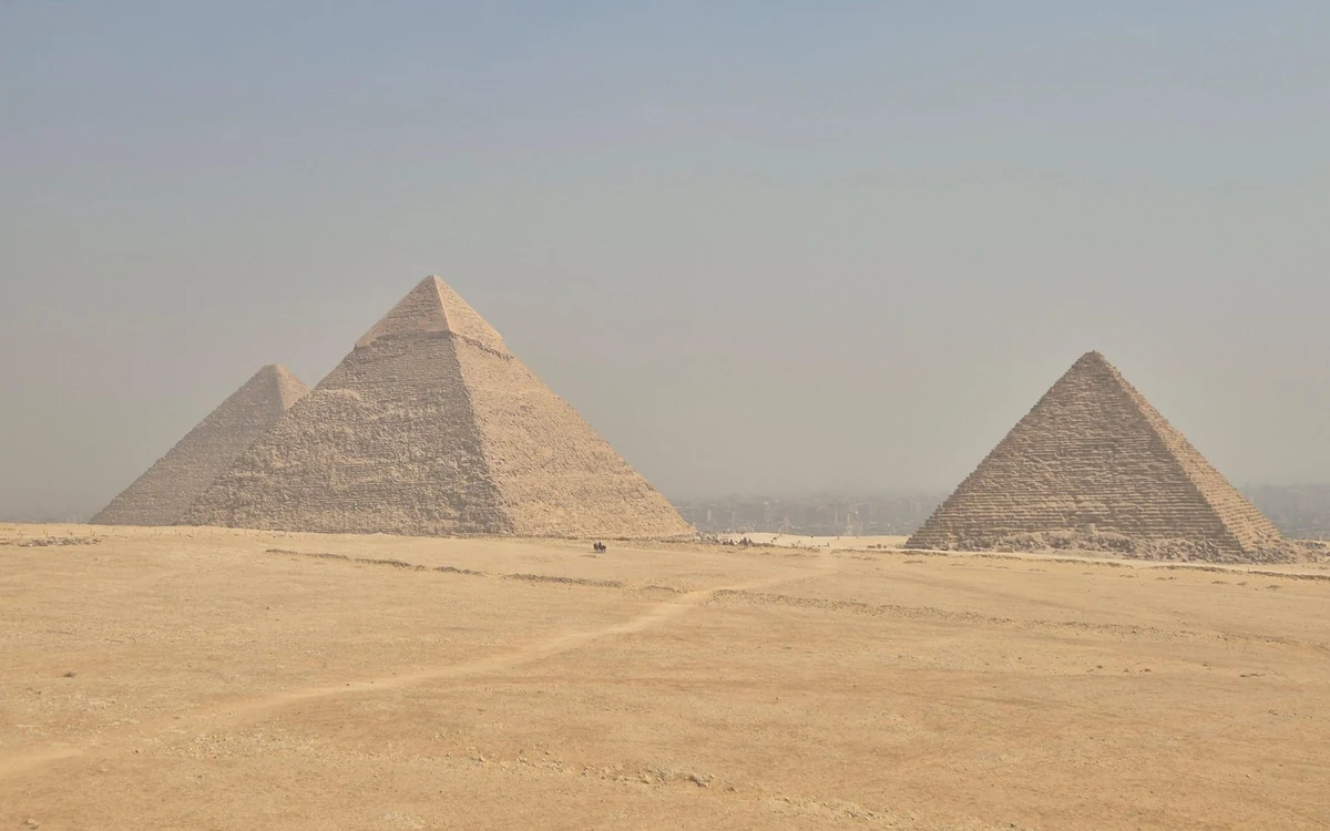 The three pyramids of Giza seen across the desert sand